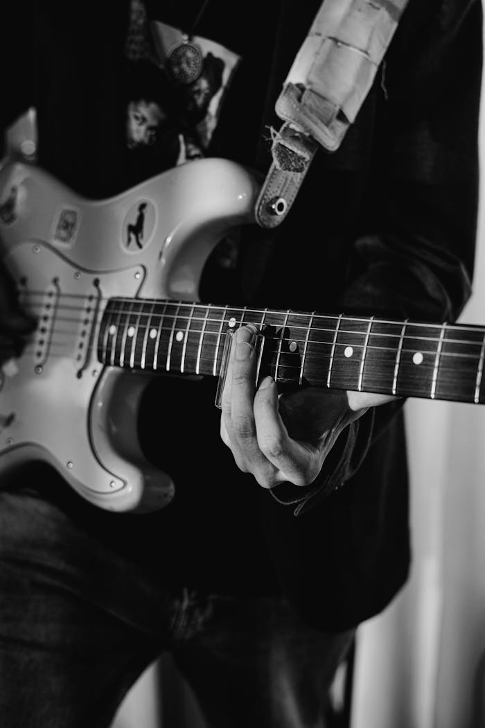 services-04 Black and white close-up of a musician playing an electric guitar.