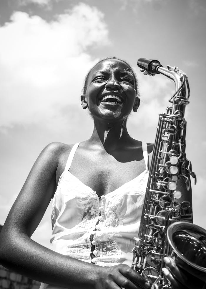 Black and white portrait of a joyful woman saxophonist outdoors in Nairobi.